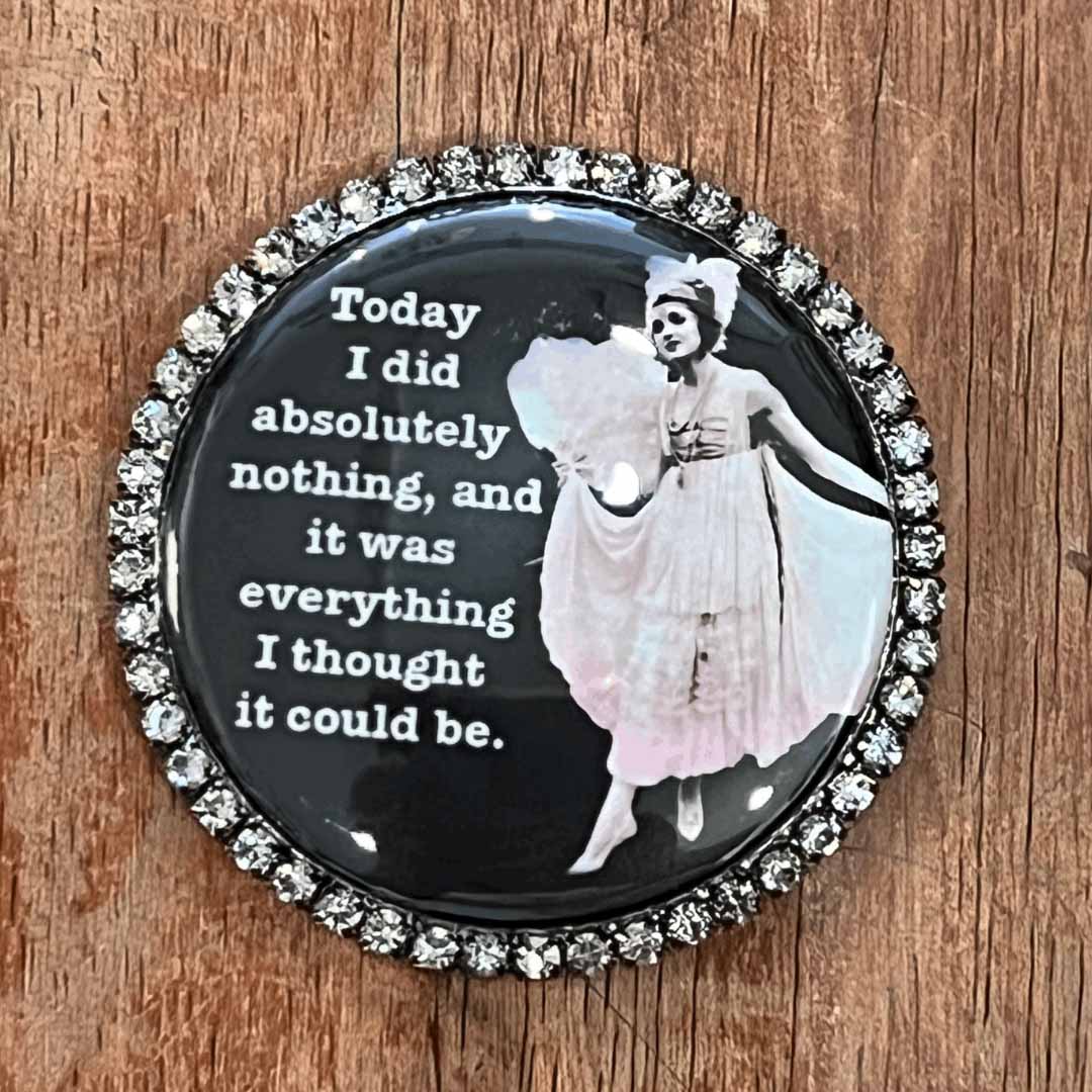 Round magnet with a quote and a person in a white dress on a wooden surface