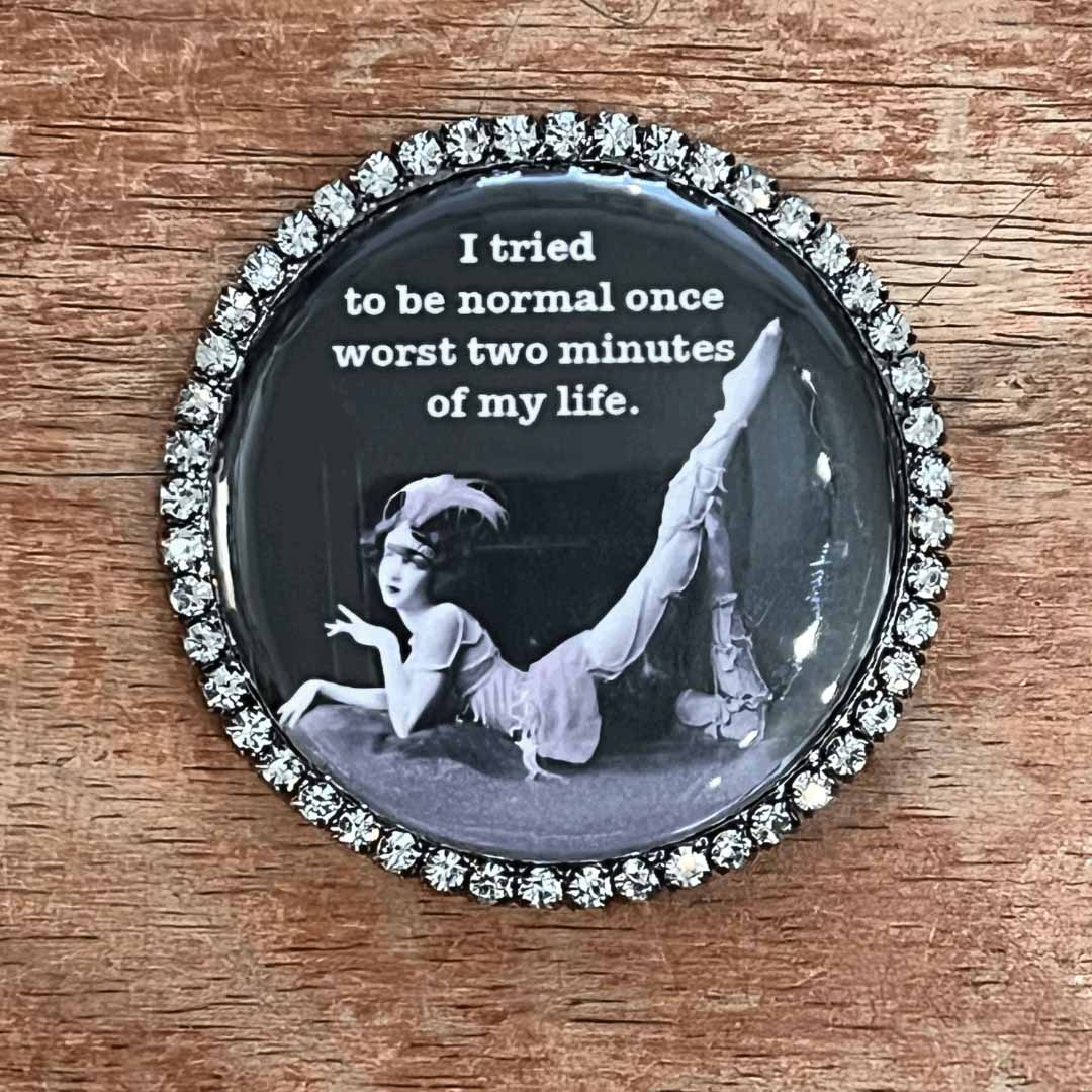 Circular magnet with a black and white image of a person and text on a wooden surface