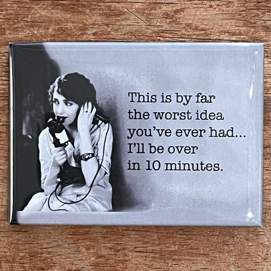 Fridge magnet with black and white photo of a woman on the phone and humorous text on a wooden surface.