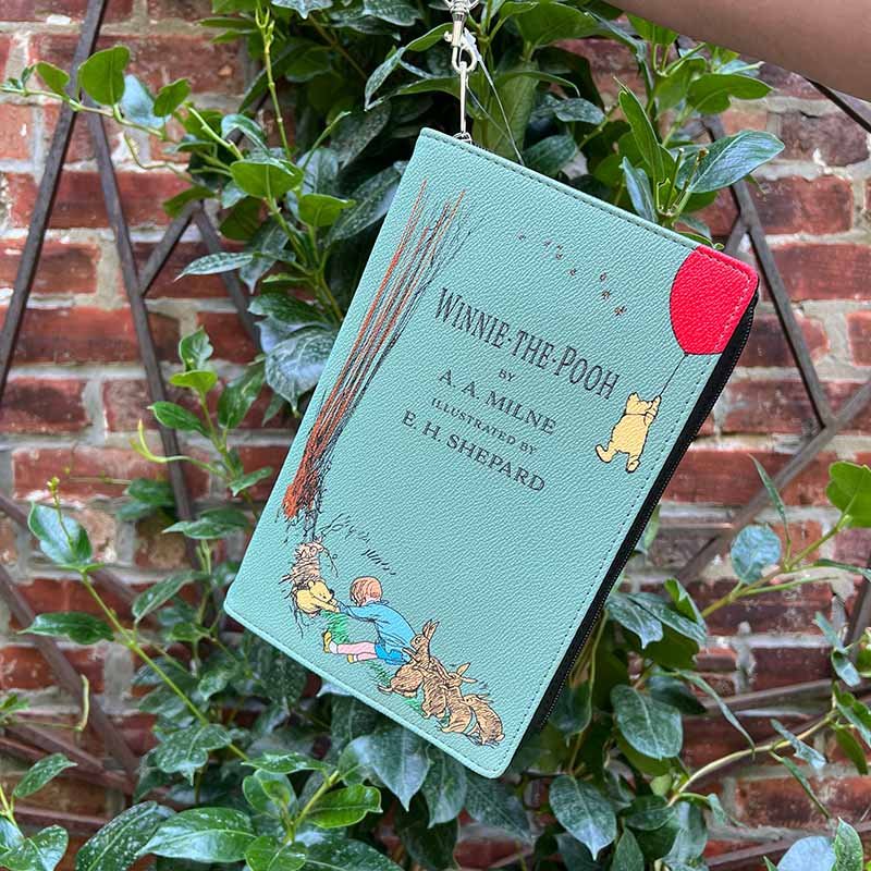 Front of Winnie the Pooh Storybook purse with graphic of Christopher robin pulling Pooh out of a whole, top graphic of pooh floating up with a red balloon