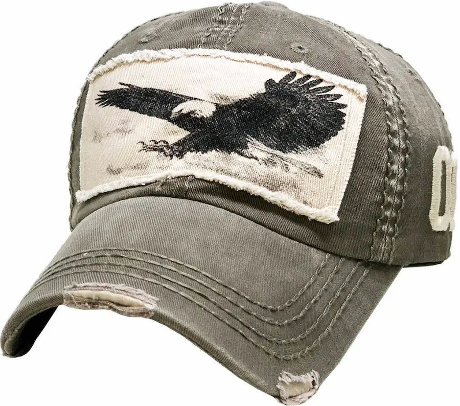 A distressed vintage ball cap with a picture of an eagle embroidered on. It is a worn Olive fabric. On a black background