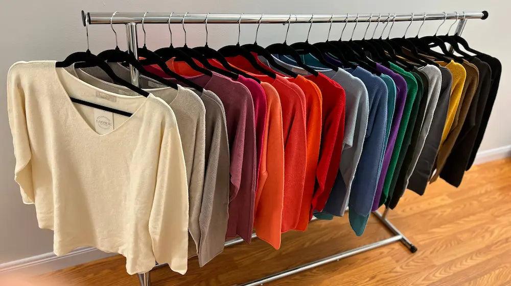 V-neck knit sweater in assorted solid colors hanging on a retail rack