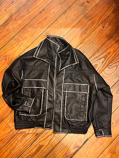 Women's oversized pocket biker jacket in black faux leather with silver trim, flat lay