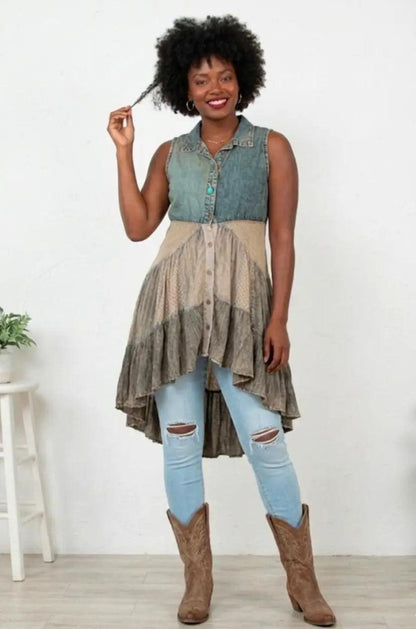 Woman wearing a layered outfit with a denim top, beige dress, and blue jeans, standing against a white background.
