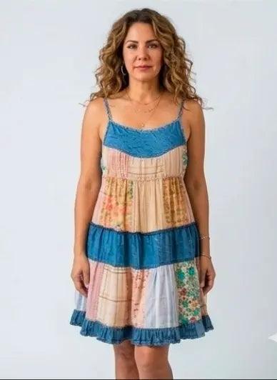Woman wearing a festival fit - a colorful floral and denim patchwork dress with flattering tie back to give a flattering fit, against a white background