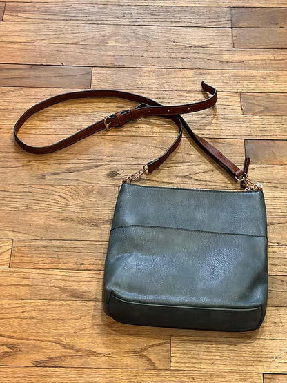 Blue leather handbag with brown strap on a wooden floor