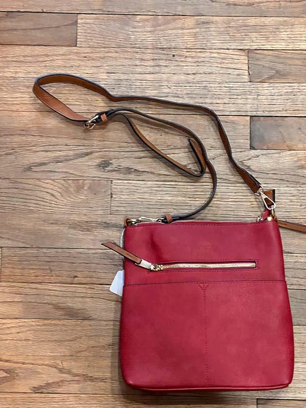 Red handbag with a strap on a wooden surface