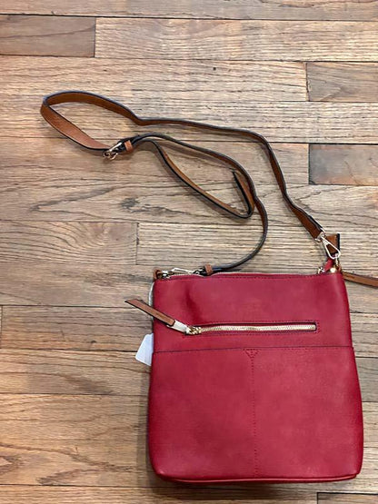 Red handbag with a strap on a wooden surface