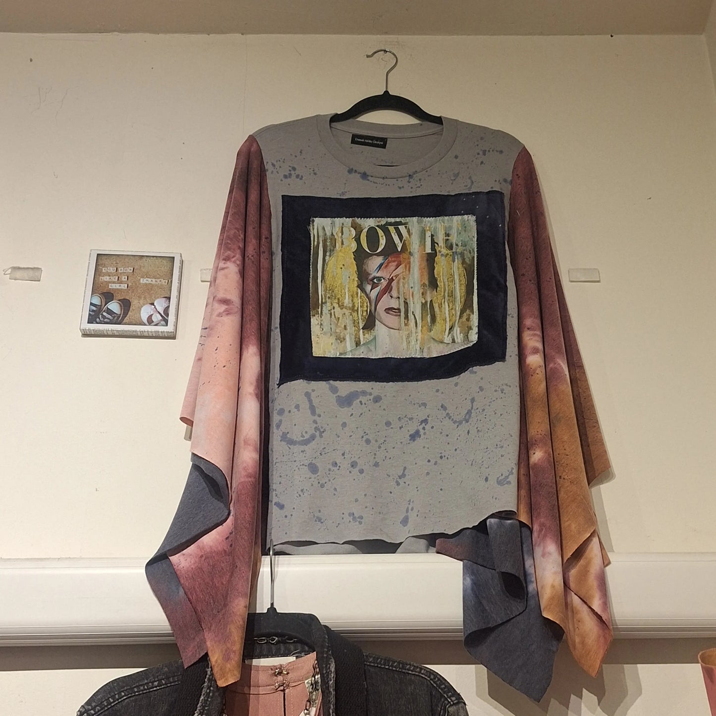 Custom made David Bowie poncho hanging on the wall next to a picture that says Run like a girl