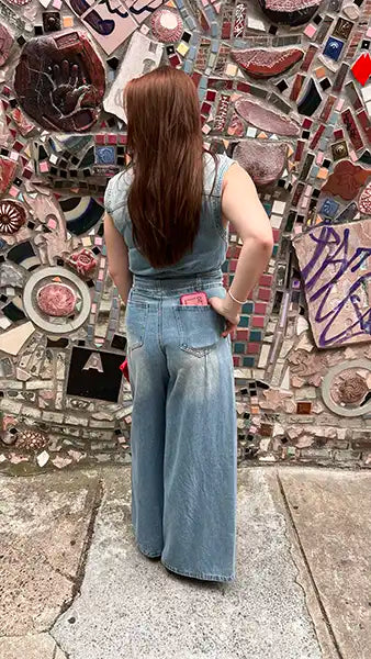 Light blue denim jumpsuit back view with high collar, belted waist, wide legs.