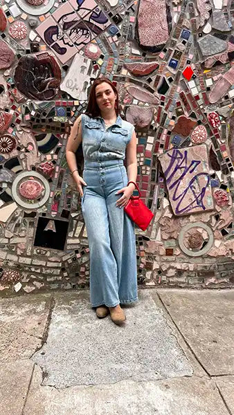 Light blue denim jumpsuit front view with fitted waist, sleeveless collar, wide cuffs.