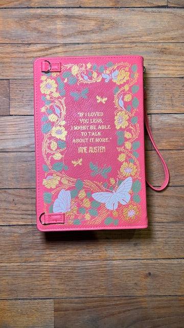 Pink notebook with floral design and quote on a wooden surface