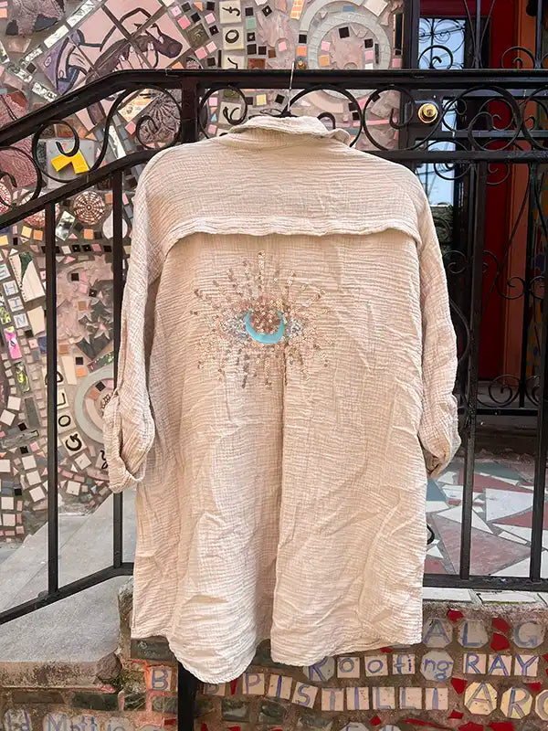 Beige textured garment with floral embroidery on a decorative staircase