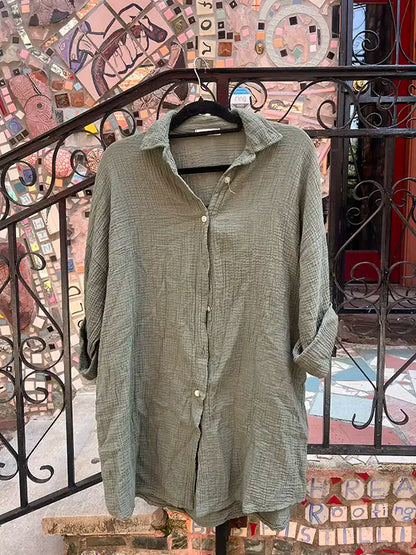 Green button-up shirt on a hanger with a mosaic wall background