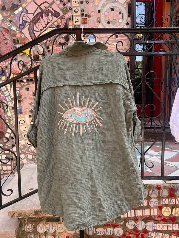 Green linen shirt with an eye design on a decorative staircase background
