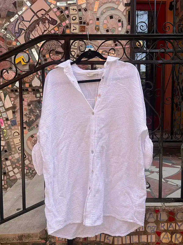 White shirt on a hanger against a decorative wall with mosaic tiles.