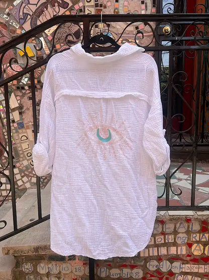 White dress with a design on a hanger against a decorative wall.