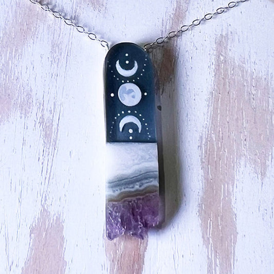 Necklace with a pendant featuring moon phases on a wooden surface