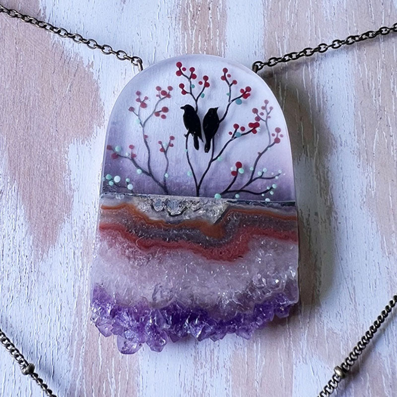 Necklace with a pendant featuring two birds on a branch with red berries against a purple and white background.