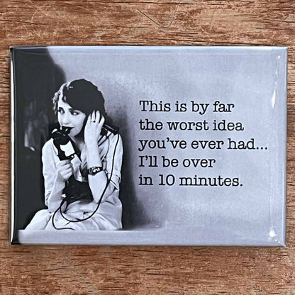 Fridge magnet with black and white photo of a woman on the phone and humorous text on a wooden surface.