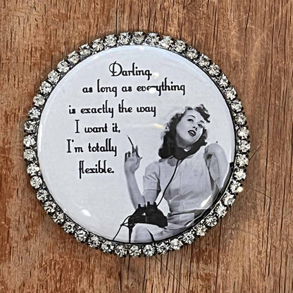 Round decorative magnet with a black and white photo of a woman and text on a wooden surface