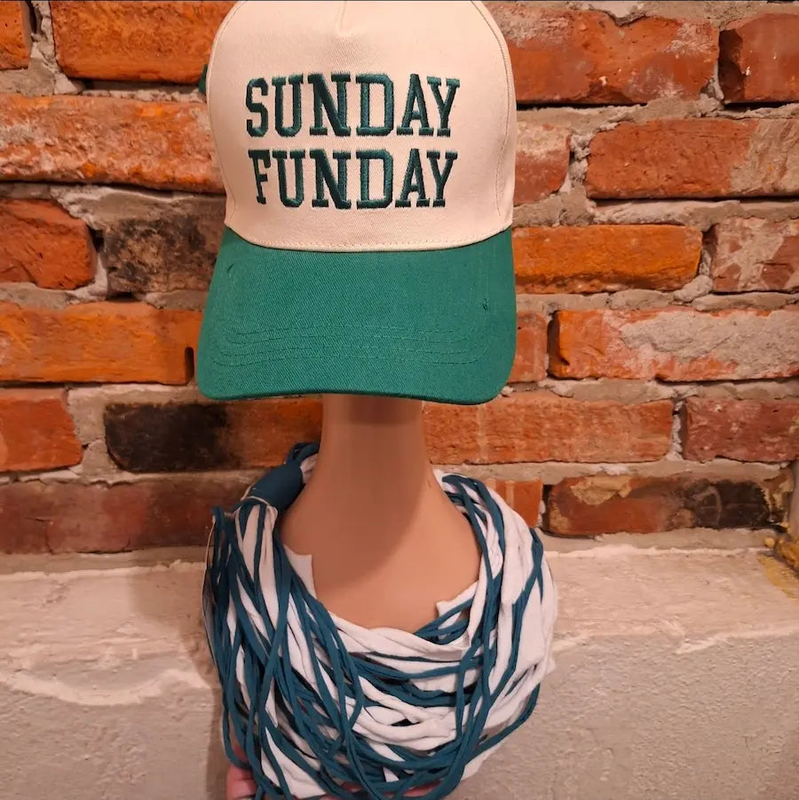 Mannequin wearing a cap with 'SUNDAY FUNDAY' text  and a shredded green and white scarf for Eagles Football Day against a brick wall.