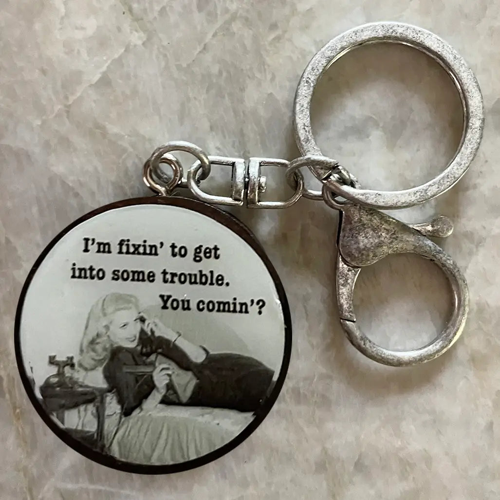 Keychain with a circular pendant featuring a black and white illustration and text on a textured surface.