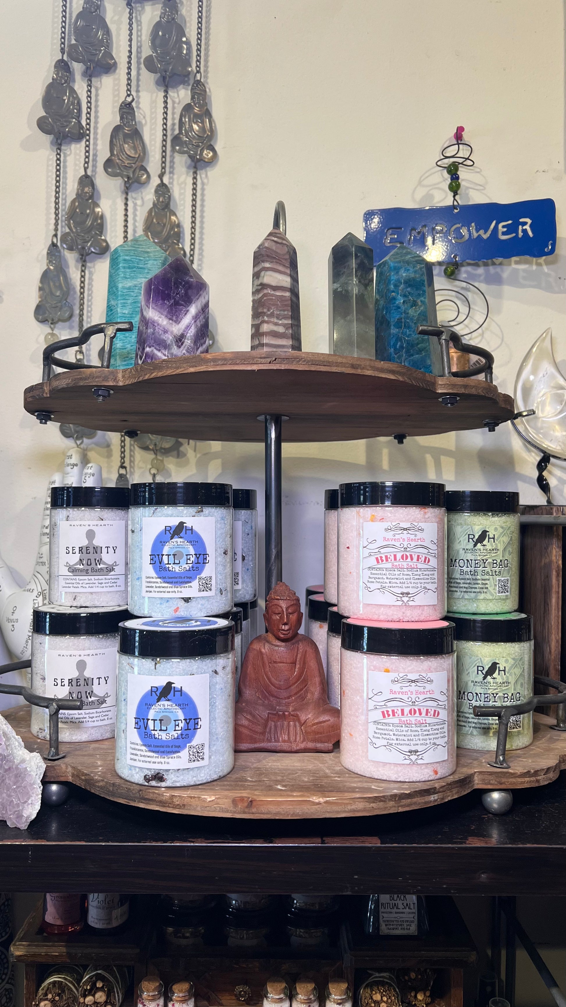 Collection of candles and crystals on a wooden shelf with a Buddha statue.