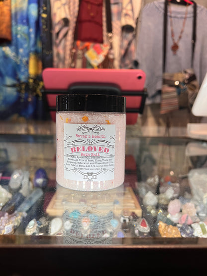 Pink container of bath salt  with the Beloved on top of lit crystal showcase