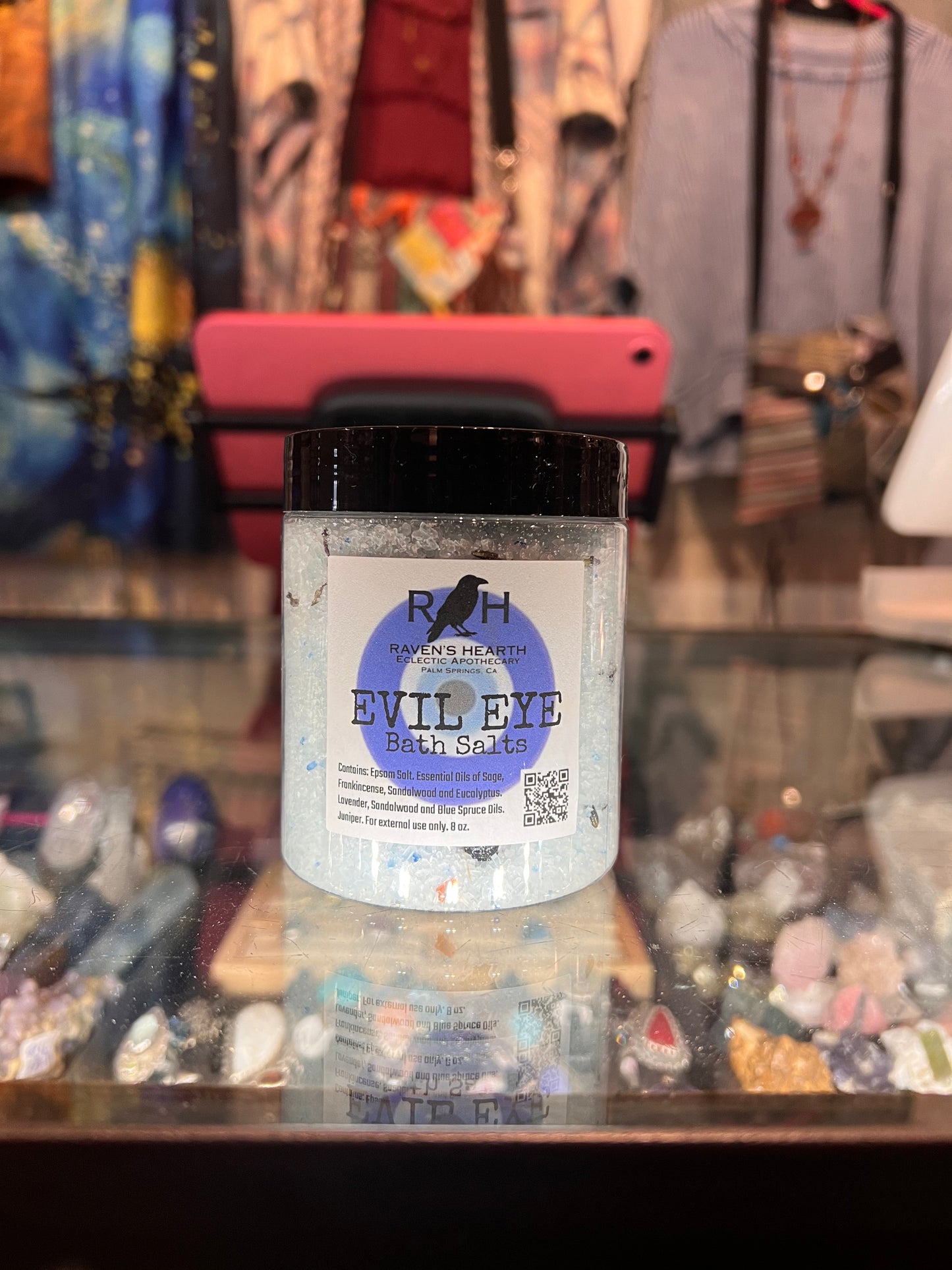 Bottle of 'Evil Eye' bath salts with a blurred store background