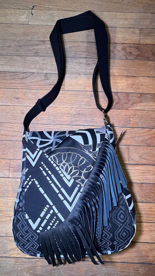 Black and white patterned bag with fringes on a wooden surface