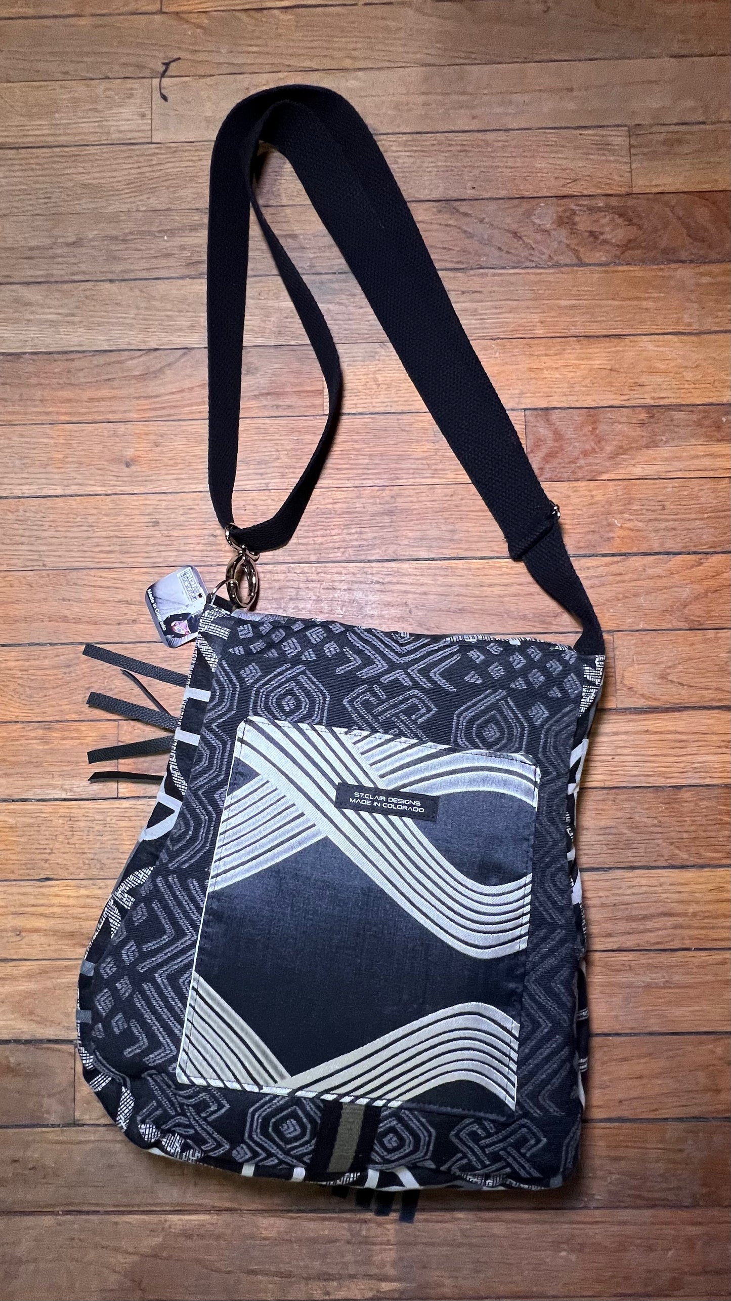Black and white patterned bag with a strap on a wooden surface