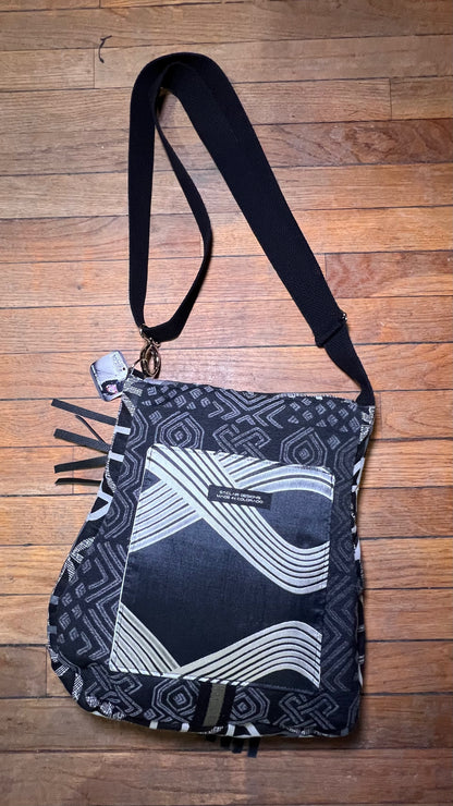 Black and white patterned bag with a strap on a wooden surface