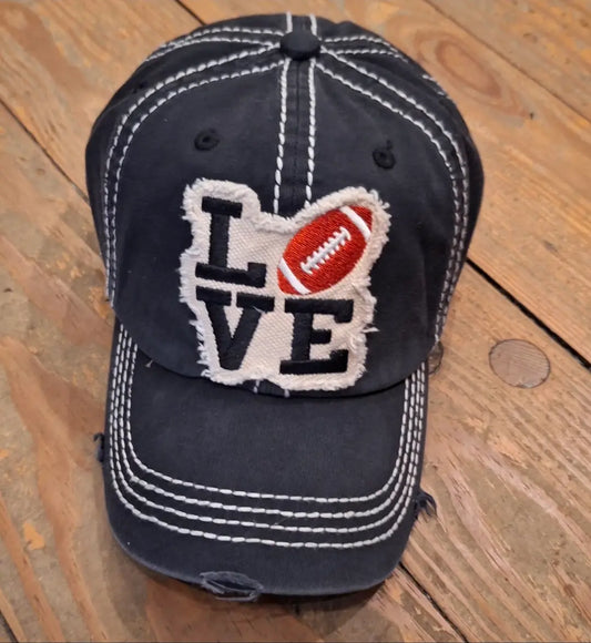A bllack baseball cap with white stitching and the word LOVE modeled after the Philadelphia LOVE Statue. The O was replaced with a football to support Philly football teams like the Philadelphia Eagles