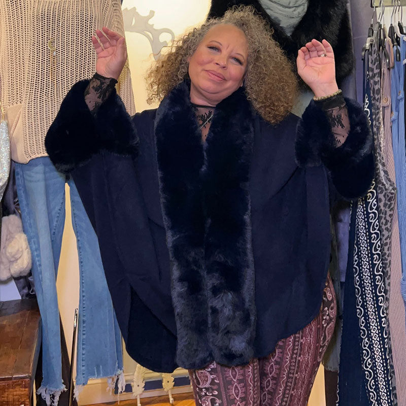 person wearing navy blue cape with arms up showing the form of the cape 