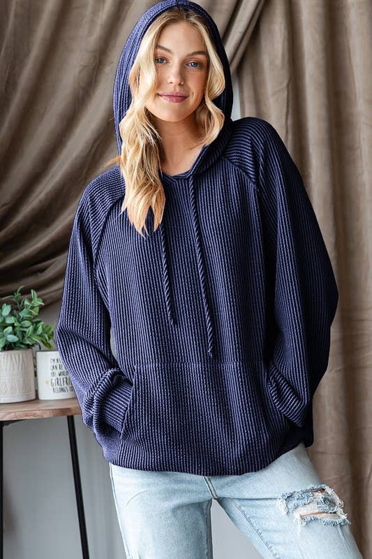 Model wearing a navy ribbed hoodie with hood and drawstring with ripped jeans