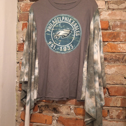 Philadelphia Eagles handmade Poncho hanging on a brick wall with the Eagles Football Team logo and the words Philadelphia Eagles EST 1933 on a circular patch that has been hand stitched on