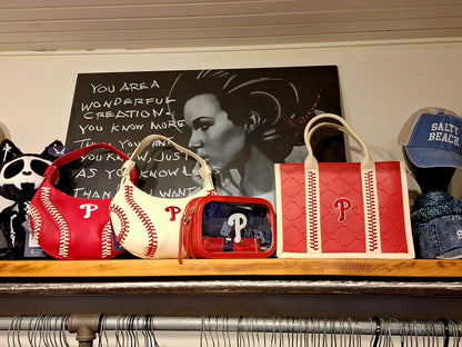 Collection of red and white handbags with a logo on a shelf, with a black and white portrait in the background.