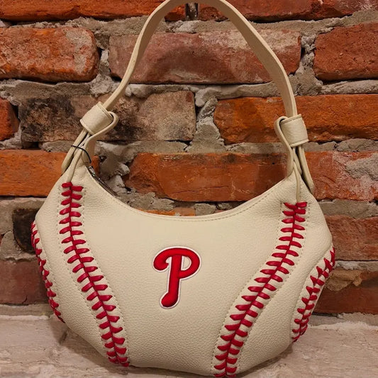 Officially lisenced MLB Baseball-shaped handbag by Montana West with red letter Phillies 'P' and baseball stitching against a brick wall background