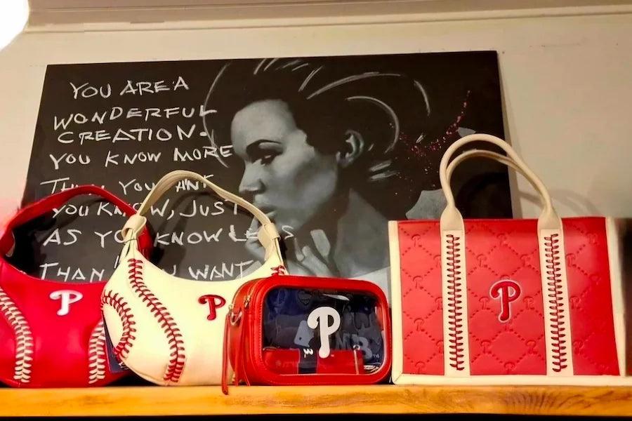 White hobo bag with red baseball stitching and Phillies P, shown with top handles