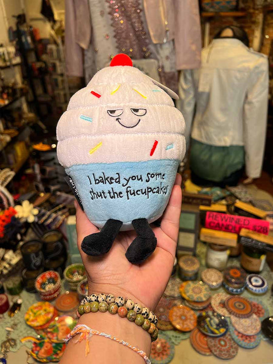 Plush cupcake gag toy with embroidered smile and message on blue frosting