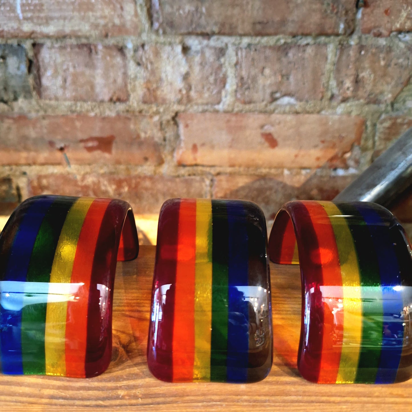 Three stained glass rainbow on a wooden surface with a brick wall background