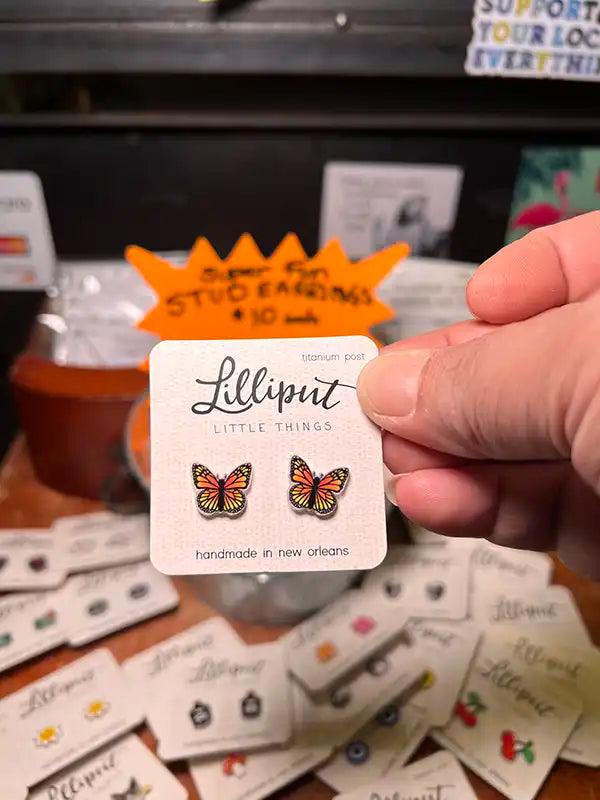 Butterfly stud earrings with orange and black enamel on small round backing cards