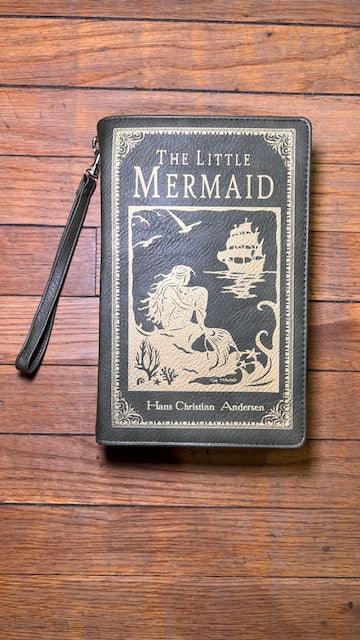 Wristlet with 'The Little Mermaid' book design on a wooden surface. included a crossboy strap