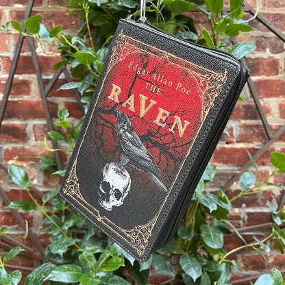 Storybook handbag with 'The Raven'  by Edgar Allen Poe featuring a raven and skull, hanging against a brick wall with greenery.