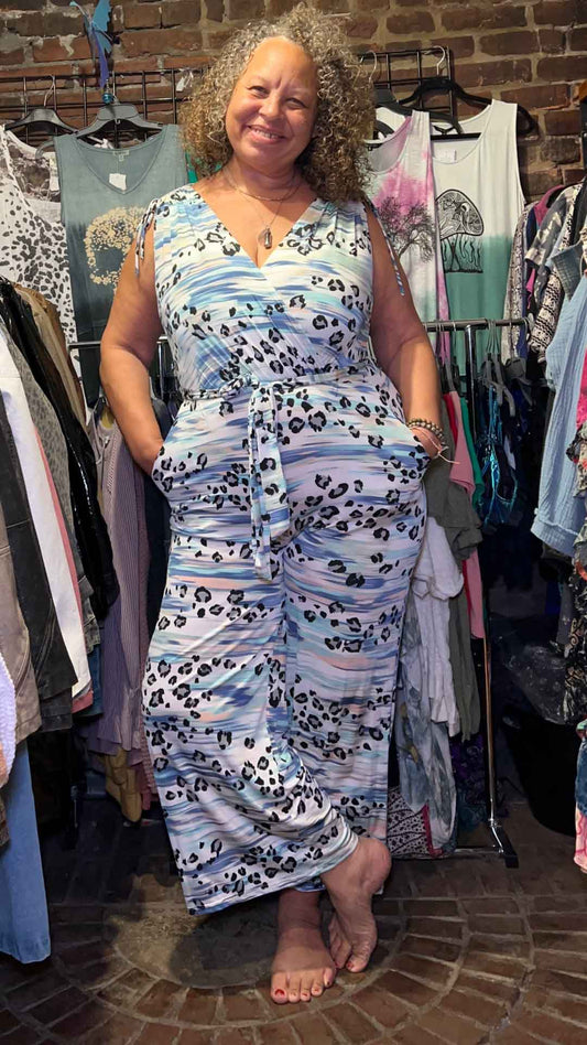 model wearing V-neckline jumpsuit with hands in the pocket and one leg crossed over the other