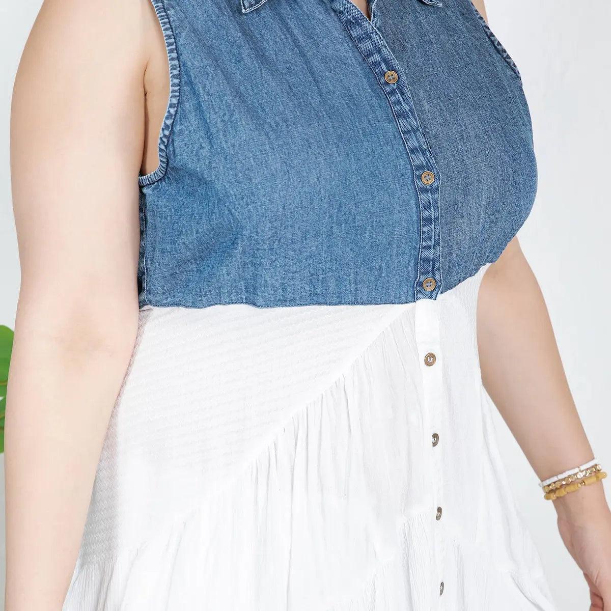 Person wearing a button down blue denim top and white skirt on a plain background