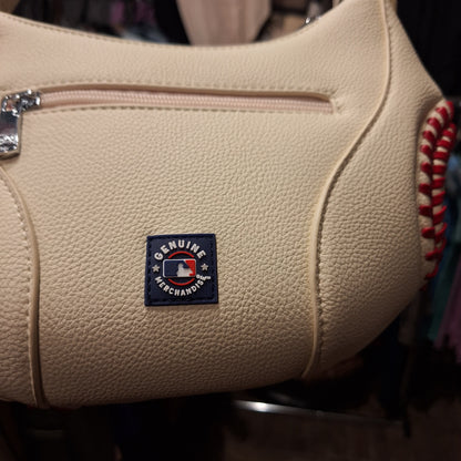 Beige leather bag with a 'Genuine Merchandise' label on a blurred background