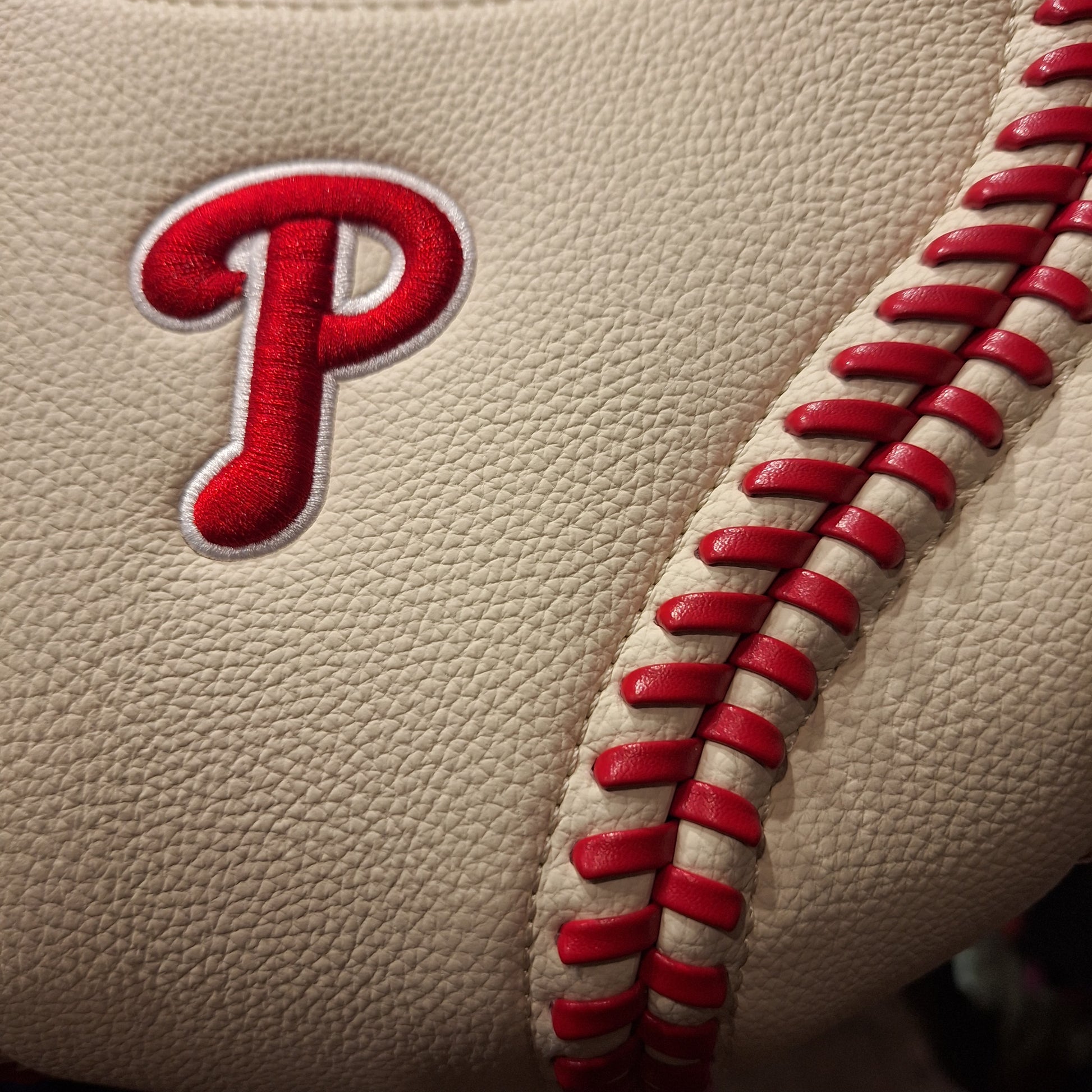 Baseball with red stitching and a red 'P' logo on beige background
